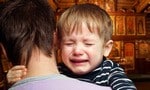 Crying child in the arms of his father